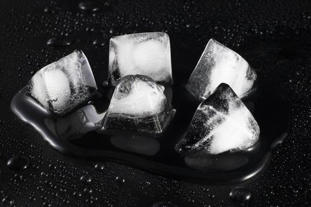 melting ice on a black background with water droplets outsideの写真素材