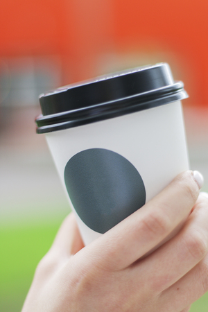 Coffee Cup with Sticker for Logo in Womans Hand with Shallow DOFの写真素材