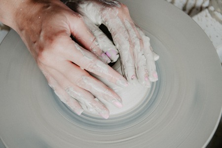 Creating a jar or vase of white clay close-up. Woman hands making clay jug.の写真素材
