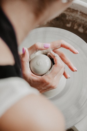Creating a jar or vase of white clay close-up. Woman hands making clay jug.