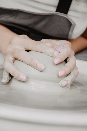 Creating a jar or vase of white clay close-up. Woman hands making clay jug.の写真素材