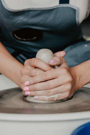 Creating a jar or vase of white clay close-up. Woman hands making clay jug.の写真素材