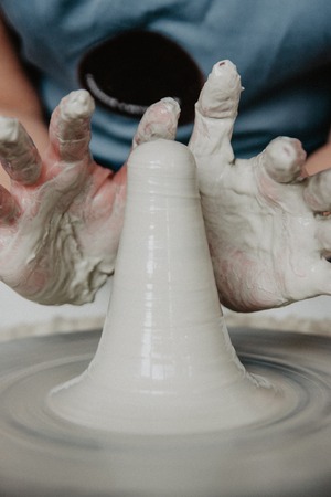 Creating a jar or vase of white clay close-up. Woman hands making clay jug.