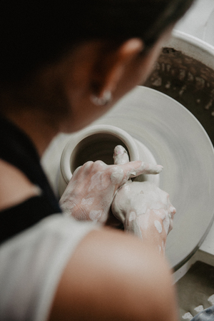 Creating a jar or vase of white clay close-up. Woman hands making clay jug.の写真素材