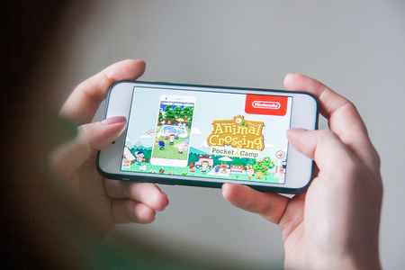 Los Angeles, California, USA - 25 February 2019: Hands holding a smartphone with Nintendo Animal Crossing game on display screenのeditorial素材