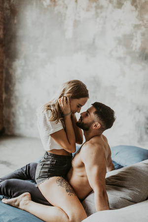 beautiful loving couple kisses and cuddles in bedの写真素材