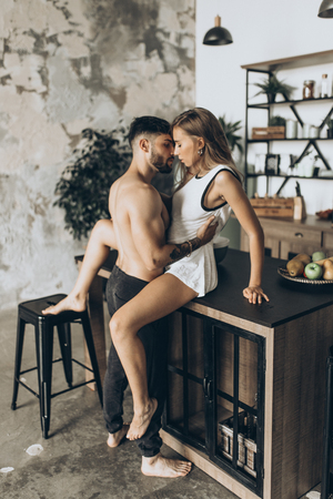 Beautiful loving couple kissing in the kitchenの写真素材