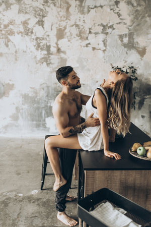 Beautiful loving couple kissing in the kitchenの写真素材