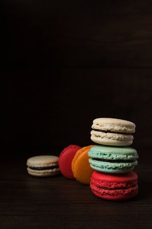 Beautiful colorful desserts. French macaroons on a dark wood backgroundの写真素材
