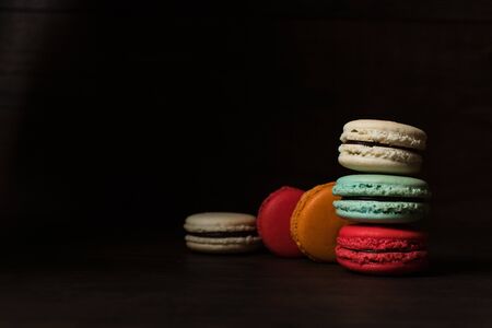 Beautiful colorful desserts. French macaroons on a dark wood backgroundの写真素材