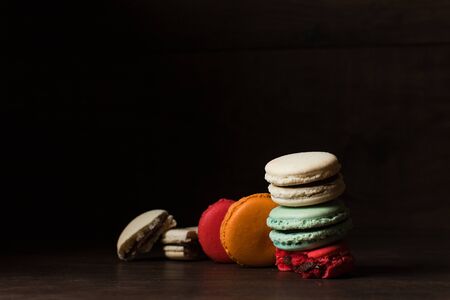 Beautiful colorful desserts. French macaroons on a dark wood backgroundの写真素材