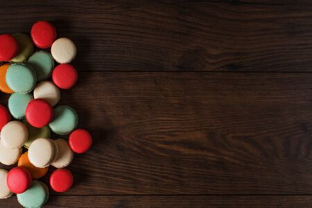 Beautiful colorful desserts. French macaroons on a dark wood backgroundの写真素材