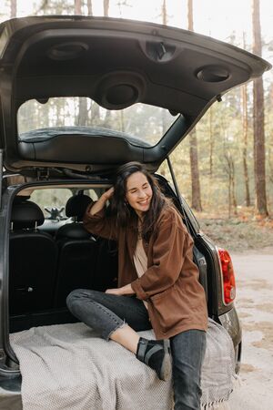 Young beautiful girl relax sitting on a car trunkの写真素材