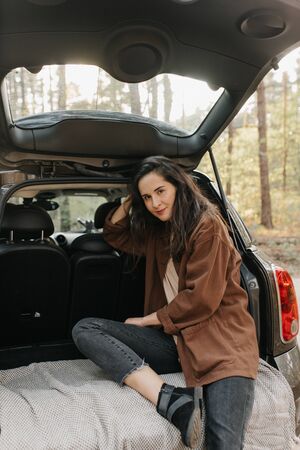 Young beautiful girl relax sitting on a car trunkの写真素材