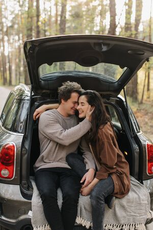 Young beautiful couple relaxing together sitting on a car trunkの写真素材