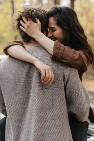 beautiful young couple in love kisses and hugs sitting on a carの写真素材