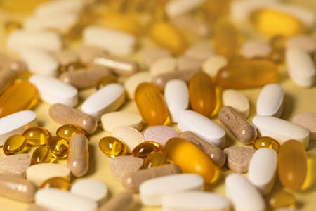 A lot of pills on a yellow background.