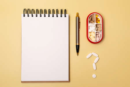 White and orange pills lie around an open notepad. flat lay.の写真素材