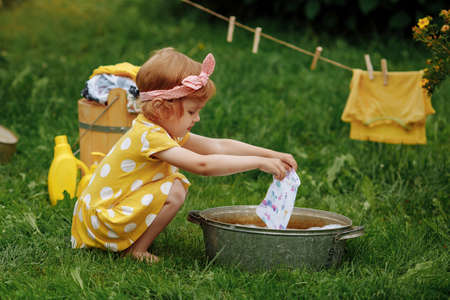 Little cute girl wipes her forehead after finishing washing in nature.の写真素材