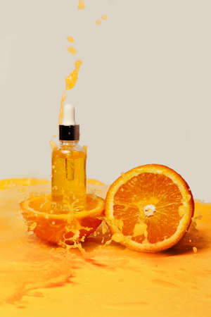 A bottle of body butter and oranges among splashes of orange juice.の写真素材
