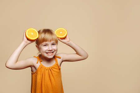Little girl making herself ears out of orangesの写真素材