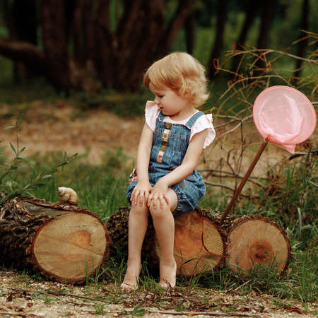Charming little girl laughs and wonders looking at a big snail.の写真素材