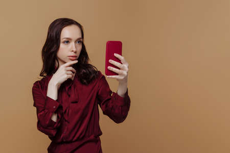 Beautiful young woman in red on a brown background.