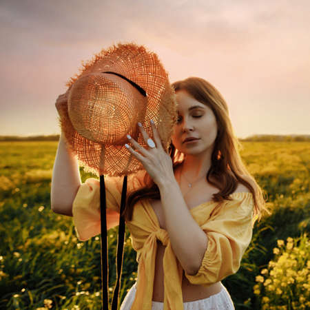 Woman in the field at sunset in the summerの写真素材