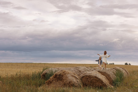 Mom and daughter are sitting on haystacksの写真素材