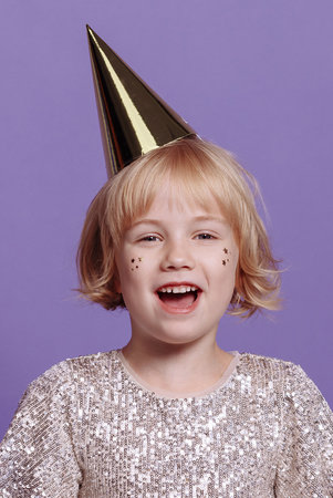 Child in a festive cap on a purple background.の写真素材
