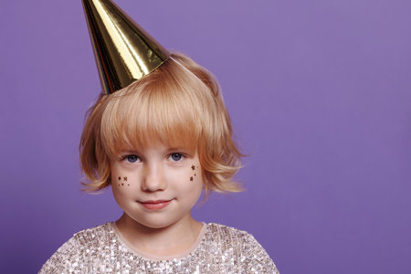 Child in a festive cap on a purple background.の写真素材