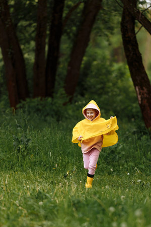 Happy funny baby under autumn shower. Girl running merrily laughing in the rainの写真素材