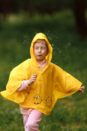 Happy funny baby under autumn shower. Girl running merrily laughing in the rainの写真素材