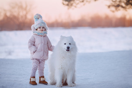 Charming little girl in a warm coat with a dog