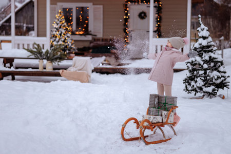 A girl is carrying an authentic wooden sleigh with giftsの写真素材