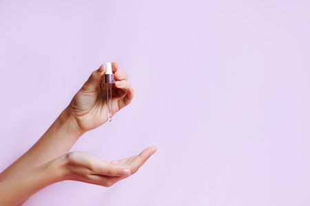 Serum bottle in female hands, side view.