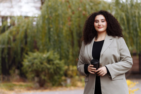 A business woman holds a glass of coffee in her hands