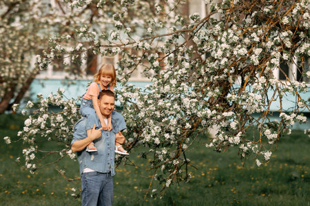Dad and daughter are hugging under an apple blossom tree.の写真素材