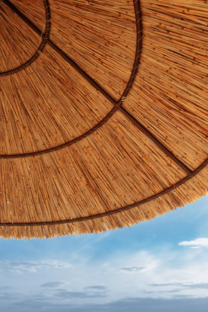 The roof of a straw umbrella against the background of blue waterの写真素材
