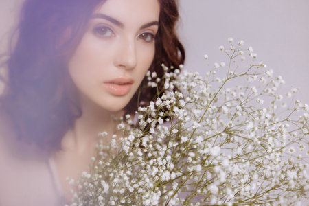 A brunette girl holds a bouquet of gypsophila flowers in her hands.の写真素材