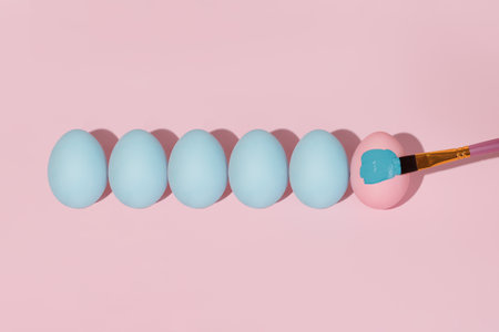 Pastel blue Easter eggs lie in a row isolated on a pink background.の写真素材