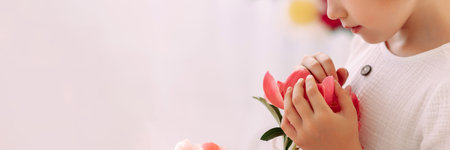 Girl 6-7 years old in a white dress holds a flowerの写真素材