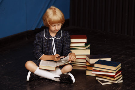 A schoolgirl sits on the floor with an open bookの写真素材