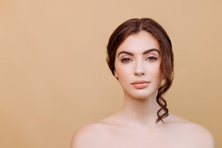 Portrait of beautiful woman looking at camera isolated on beige background.