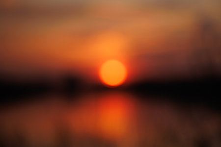 Blurred bokeh of a bright sunset on the beach and water reflectionの写真素材
