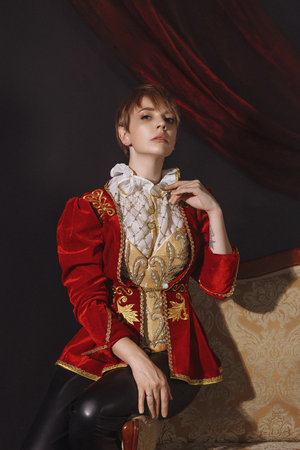 Woman in a red vintage jacket embroidered with gold patternsの写真素材