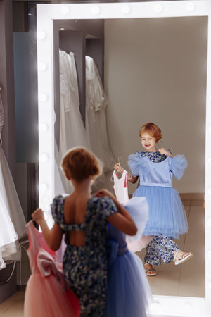 A small girl or client chooses a dress in front of a mirror.の写真素材