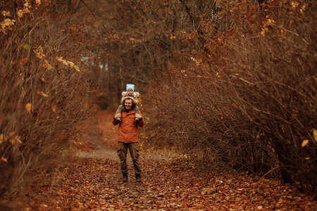 Happy family father and child daughter on a walk in the autumn leaf fall in parkの写真素材