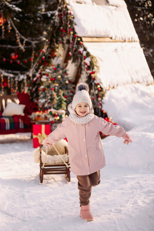 A child runs with a sled along a decorated Christmas streetの写真素材