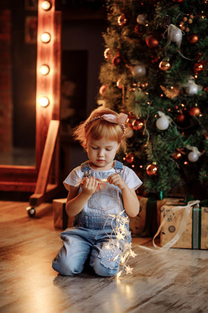 Cozy Christmas scene with child and lights near the Christmas treeの写真素材